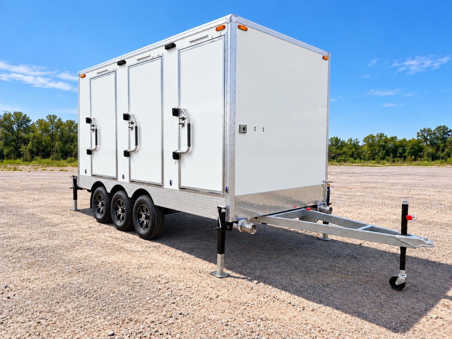 Exterior of a shower and restroom combination trailer with three stall doors and a steel tow frame